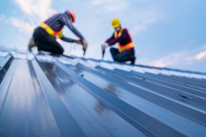 Two workers installing metal roofing